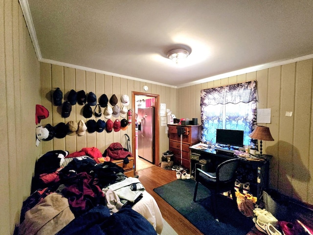 bedroom featuring stainless steel fridge, crown molding, and wood-type flooring