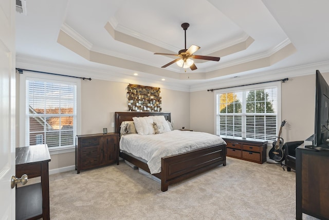 bedroom with ceiling fan, a tray ceiling, ornamental molding, and light colored carpet