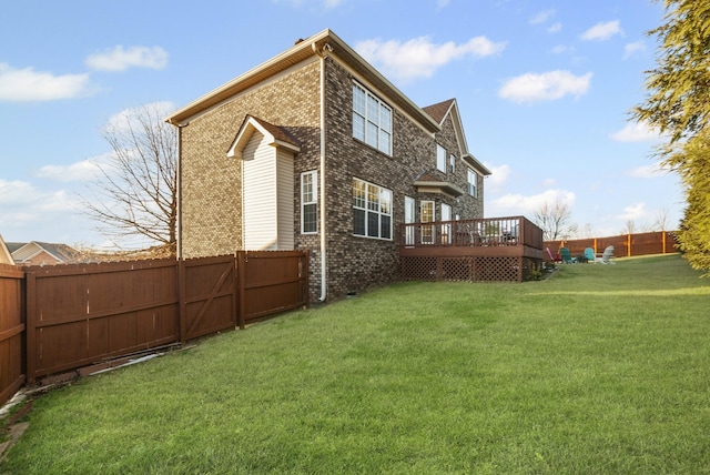 rear view of property featuring a wooden deck and a lawn