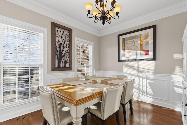 dining space featuring dark hardwood / wood-style flooring, an inviting chandelier, and crown molding