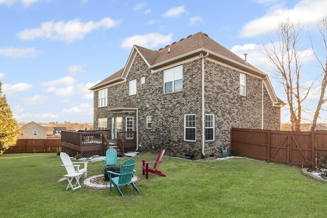 rear view of property featuring an outdoor fire pit, a yard, and a wooden deck