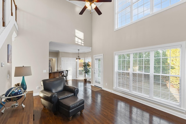 sitting room featuring a towering ceiling, ceiling fan, and dark wood-type flooring