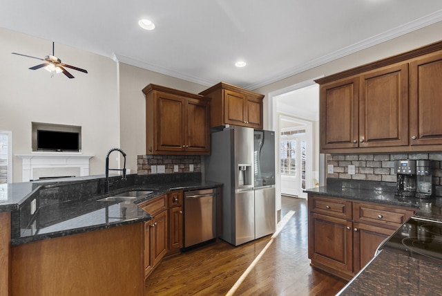 kitchen featuring stainless steel appliances, sink, backsplash, and dark stone counters