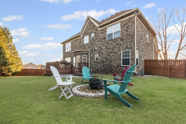 back of property featuring a lawn, a fire pit, and a wooden deck