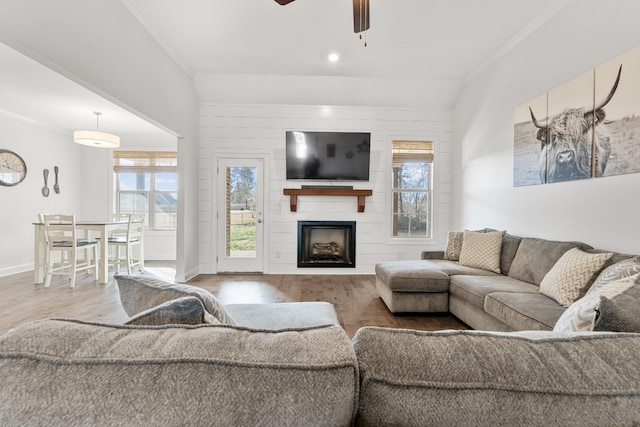 living room with vaulted ceiling, crown molding, ceiling fan, a fireplace, and hardwood / wood-style flooring