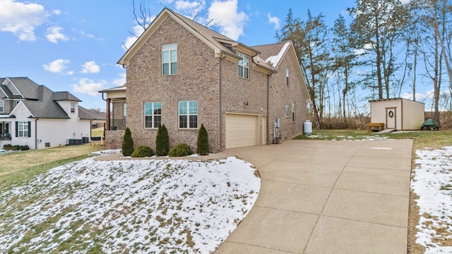 view of snow covered exterior featuring a storage shed and a garage