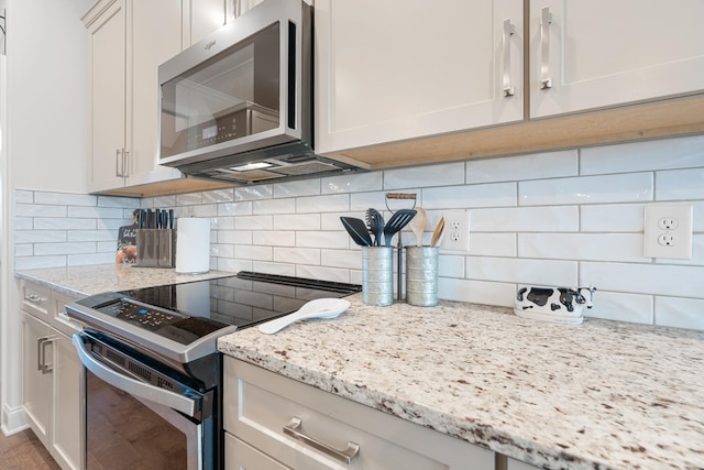 kitchen with stainless steel appliances, light stone countertops, decorative backsplash, hardwood / wood-style flooring, and white cabinets