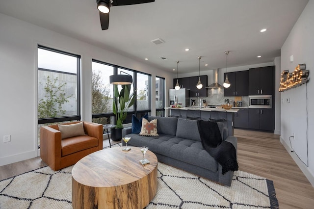 living room with ceiling fan and light hardwood / wood-style flooring