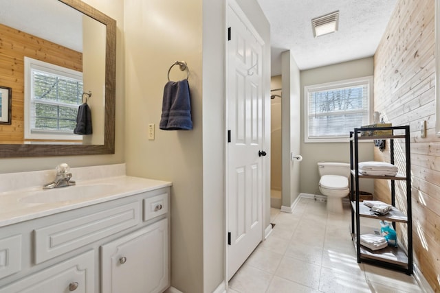 bathroom with a textured ceiling, toilet, a wealth of natural light, and wooden walls