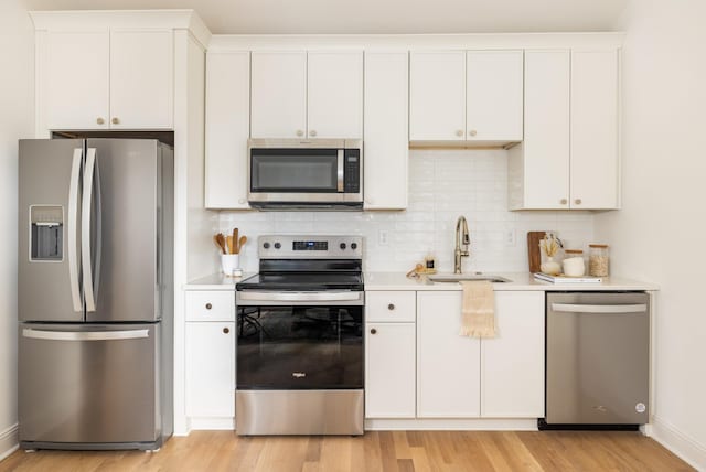 kitchen featuring sink, white cabinetry, light hardwood / wood-style flooring, backsplash, and appliances with stainless steel finishes