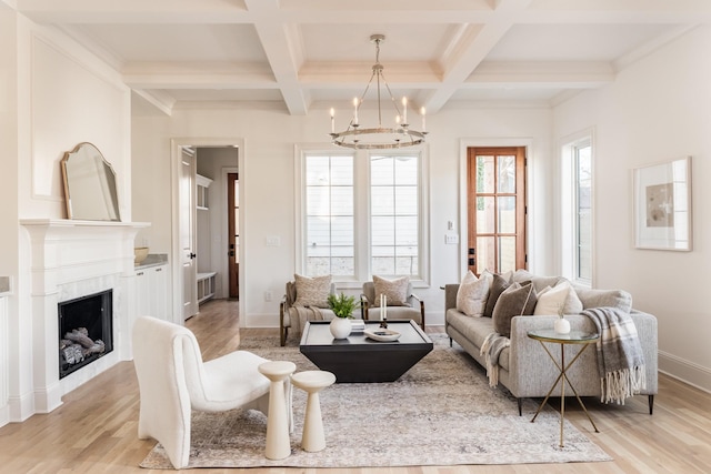 living room featuring light wood-type flooring, an inviting chandelier, and beamed ceiling