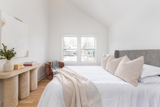 bedroom featuring high vaulted ceiling and light hardwood / wood-style flooring