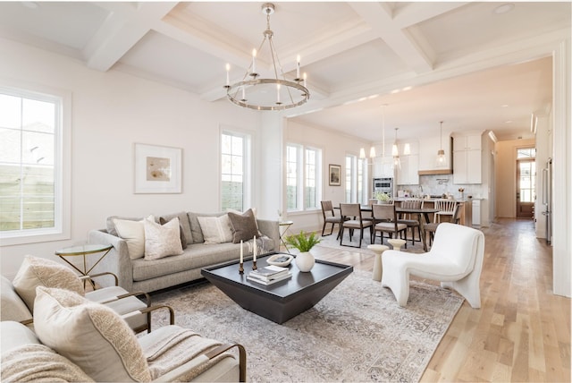 living room featuring a notable chandelier, light hardwood / wood-style flooring, coffered ceiling, and beamed ceiling