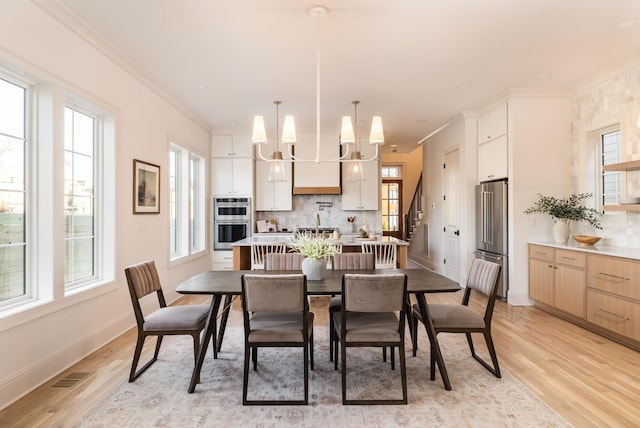 dining room featuring an inviting chandelier, ornamental molding, and light hardwood / wood-style flooring