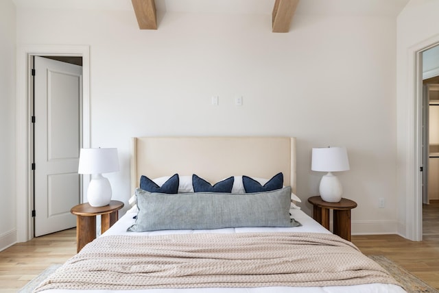 bedroom with light wood-type flooring and beamed ceiling