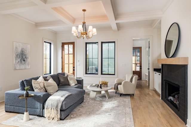 living room featuring coffered ceiling, crown molding, beam ceiling, light hardwood / wood-style flooring, and an inviting chandelier