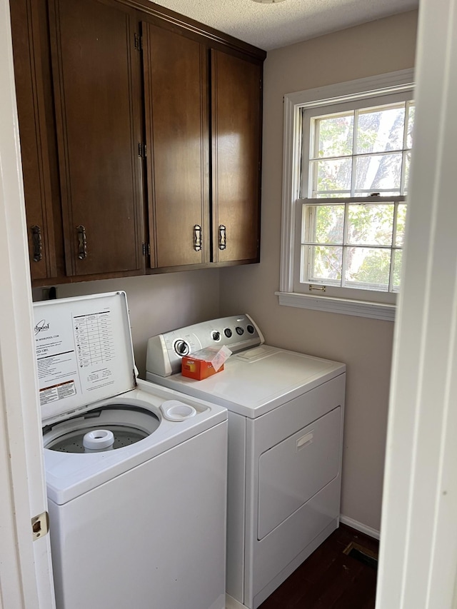 laundry room featuring a textured ceiling, cabinets, and washer and clothes dryer