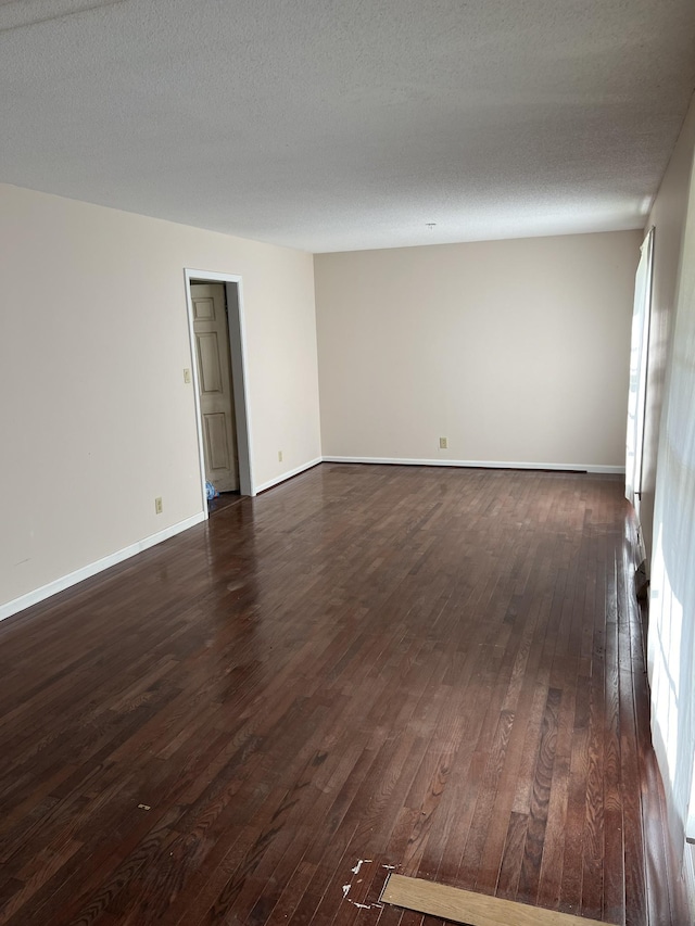 spare room featuring a textured ceiling and dark hardwood / wood-style flooring