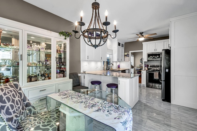 dining space with sink and ceiling fan with notable chandelier