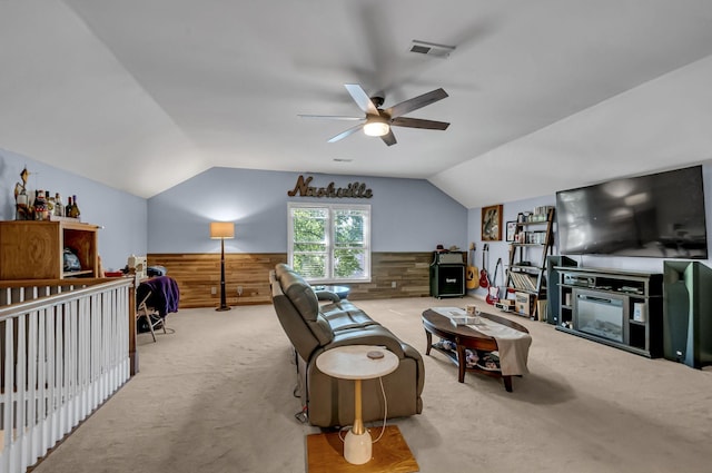 living room with vaulted ceiling, light colored carpet, ceiling fan, and wooden walls