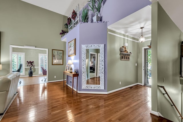 entryway with hardwood / wood-style flooring, vaulted ceiling, crown molding, and a chandelier