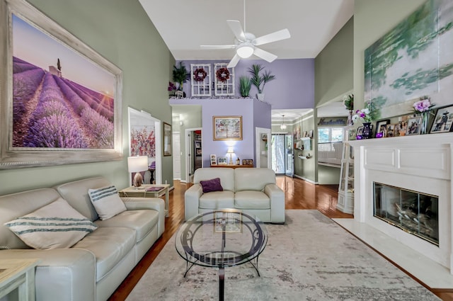 living room featuring ceiling fan, high vaulted ceiling, a fireplace, and hardwood / wood-style flooring