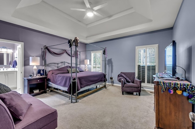 carpeted bedroom featuring ceiling fan, ensuite bathroom, and a tray ceiling