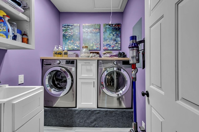 clothes washing area with separate washer and dryer and cabinets