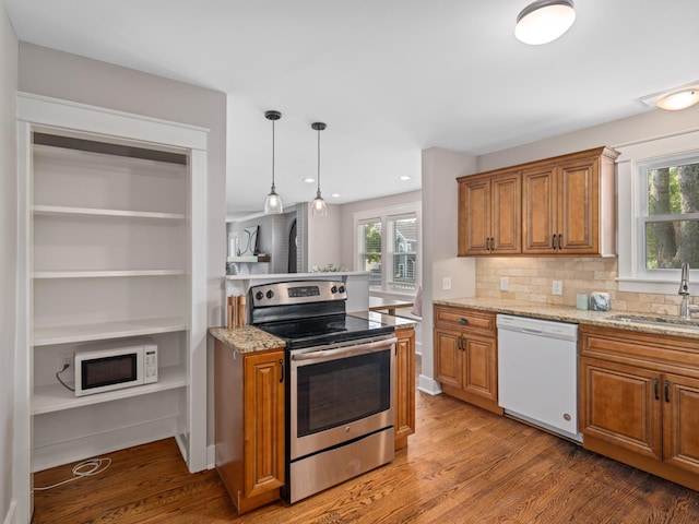 kitchen featuring sink, light stone counters, white appliances, tasteful backsplash, and hanging light fixtures