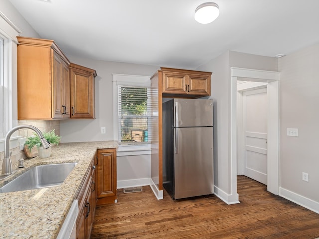 kitchen with sink, stainless steel appliances, dark hardwood / wood-style flooring, and light stone countertops