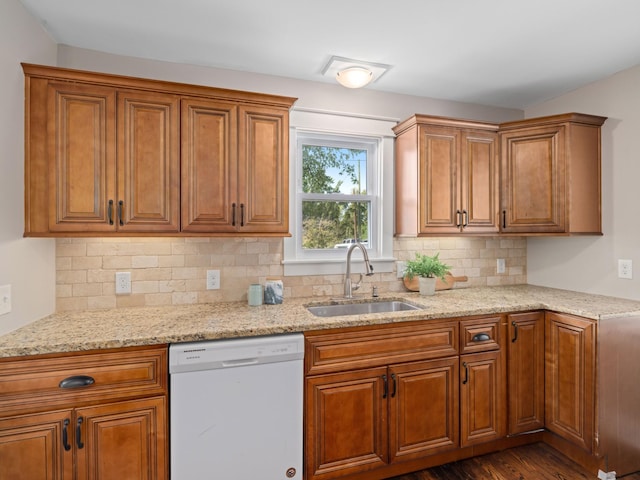 kitchen with sink, dishwasher, decorative backsplash, light stone countertops, and dark hardwood / wood-style flooring