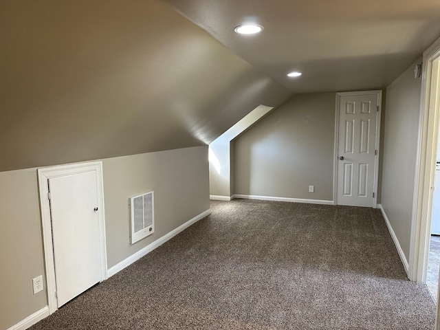 bonus room with dark colored carpet and vaulted ceiling