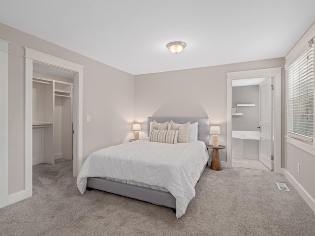 bedroom featuring ensuite bathroom, a closet, a spacious closet, and light carpet