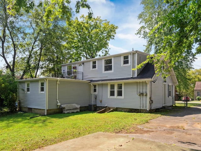 rear view of property featuring a balcony, central air condition unit, and a yard