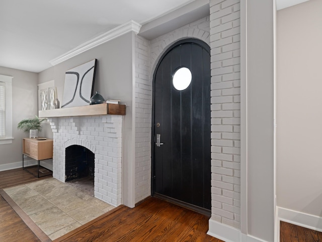 entryway featuring a brick fireplace, ornamental molding, and hardwood / wood-style flooring