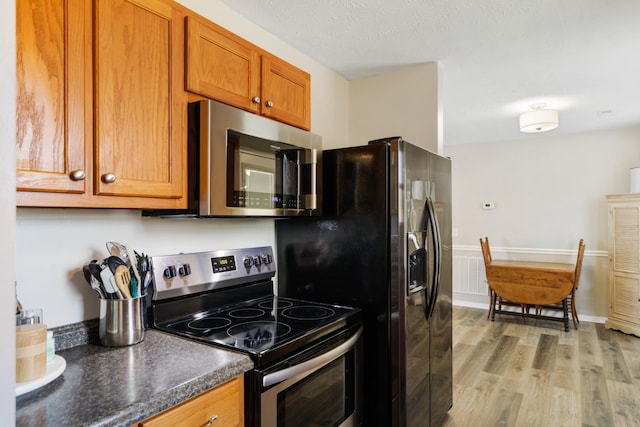 kitchen with light hardwood / wood-style floors and appliances with stainless steel finishes