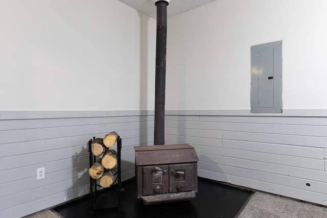 interior details with electric panel and a wood stove