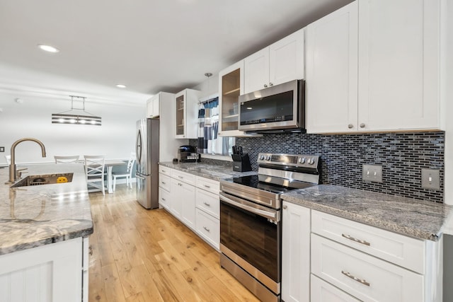 kitchen with light stone counters, pendant lighting, white cabinets, appliances with stainless steel finishes, and sink