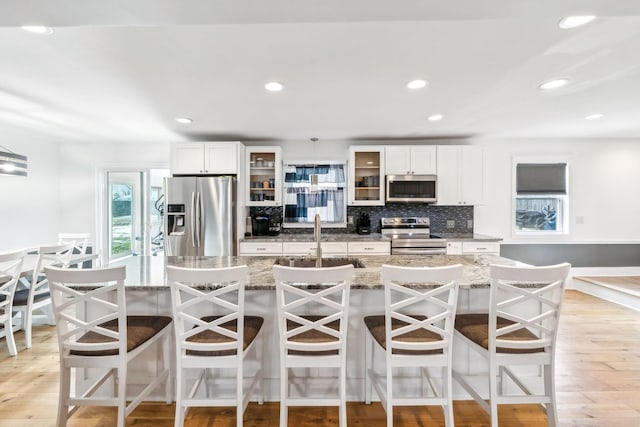 kitchen with sink, a kitchen breakfast bar, an island with sink, and appliances with stainless steel finishes