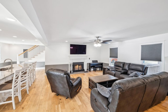 living room featuring ceiling fan, light hardwood / wood-style flooring, and sink