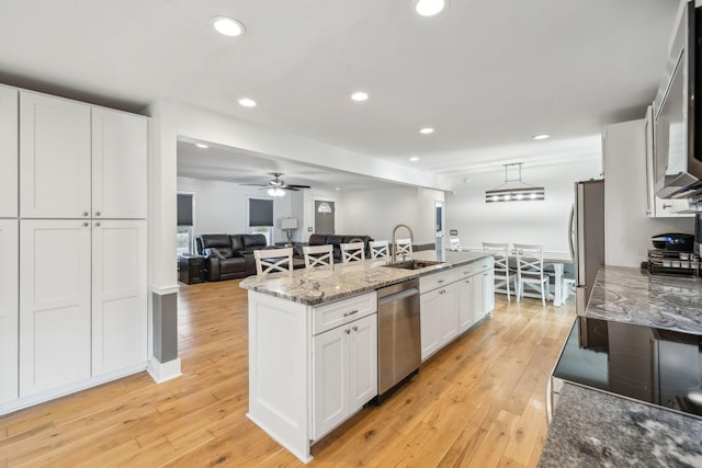 kitchen featuring appliances with stainless steel finishes, a kitchen island, sink, white cabinetry, and decorative light fixtures