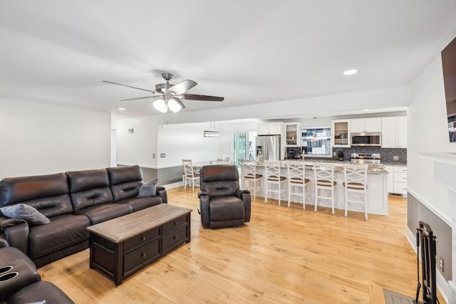 living room with ceiling fan, light hardwood / wood-style flooring, and sink