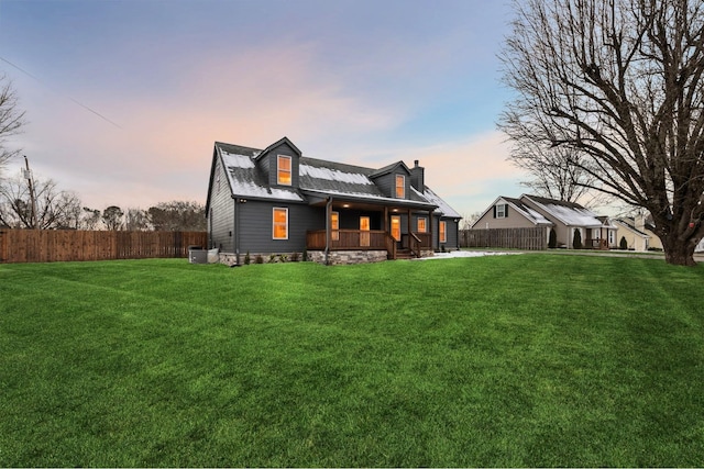 back house at dusk featuring covered porch and a yard