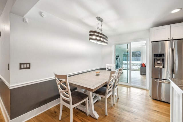 dining area with ceiling fan with notable chandelier and light hardwood / wood-style flooring