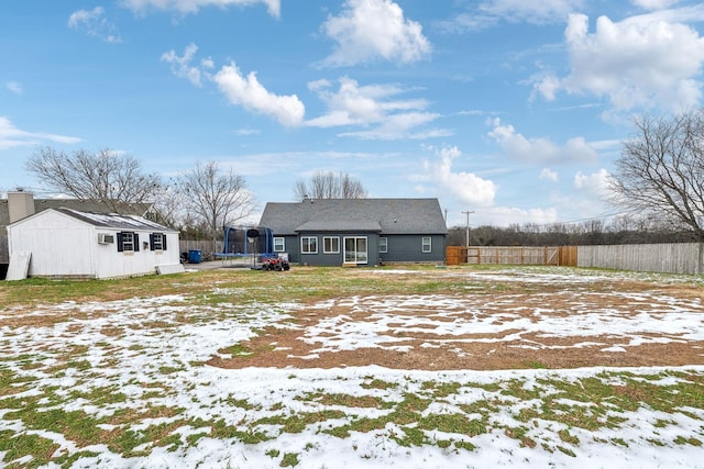 snow covered back of property with a trampoline