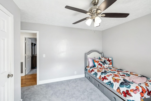 bedroom with ceiling fan, light carpet, and a textured ceiling