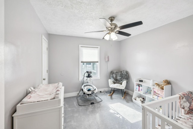 carpeted bedroom with a textured ceiling, ceiling fan, and a crib