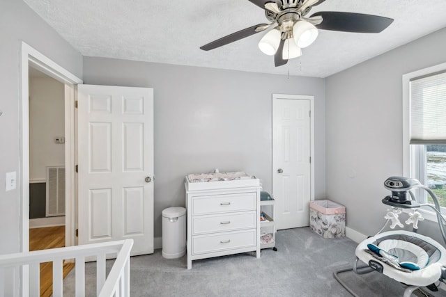 carpeted bedroom with ceiling fan and a textured ceiling