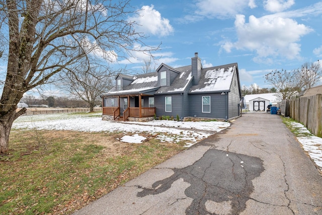 view of front of property featuring covered porch and a shed