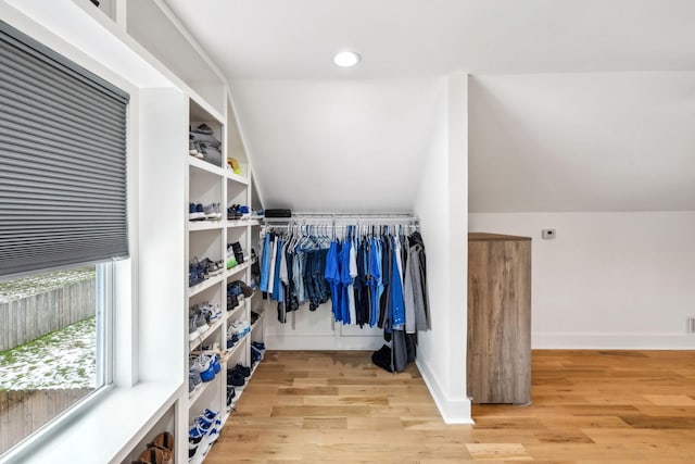 spacious closet with light hardwood / wood-style flooring and vaulted ceiling